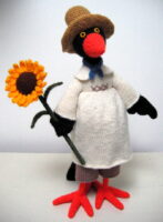 knitted toy of a crow in a farm smock and hat