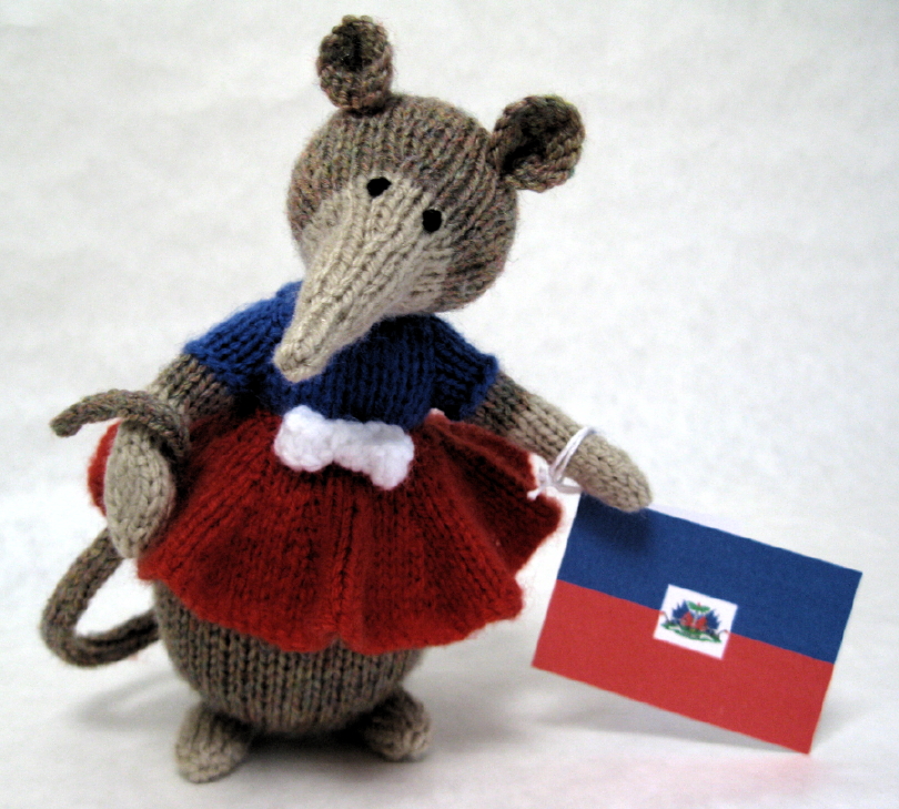 knitted toy of Aida the mouse with a Haitian flag