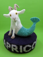 Knitted toy of a sea goat on a plinth