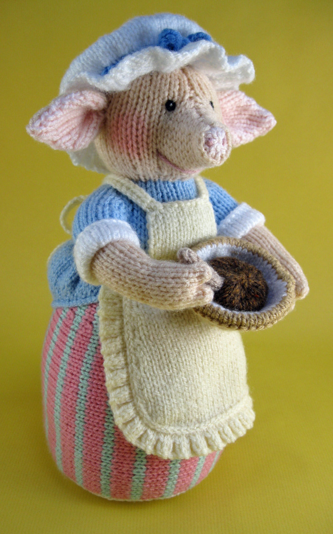 knitted toy of a pig dressed as a farmers wife with a pinny and mixing bowl