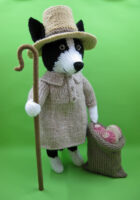 knitted toy of a collie in a farm smock with a hat and shepherds crook